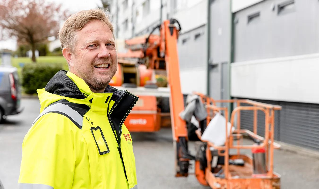 Prosjetkleder fra Bate foran en lift på byggeplass. 