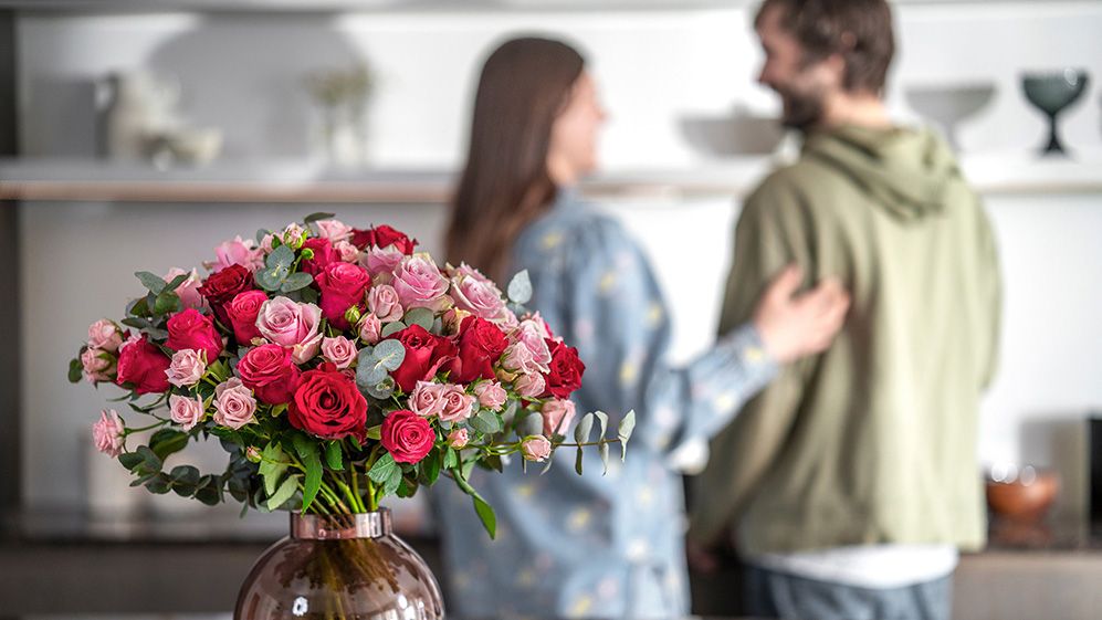 blomsterbukett i vase med mann og dame i bakgrunnen