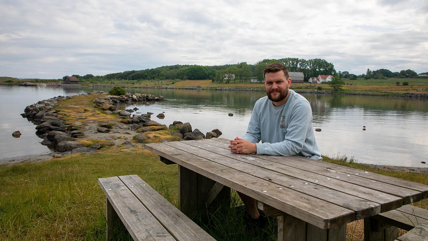 mann sitter på benk ved strand