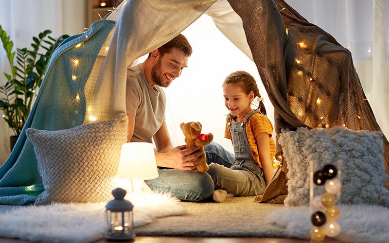 Far og datter sitter i et telt med lys