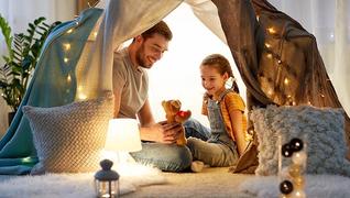 Far og datter sitter i et telt med lys