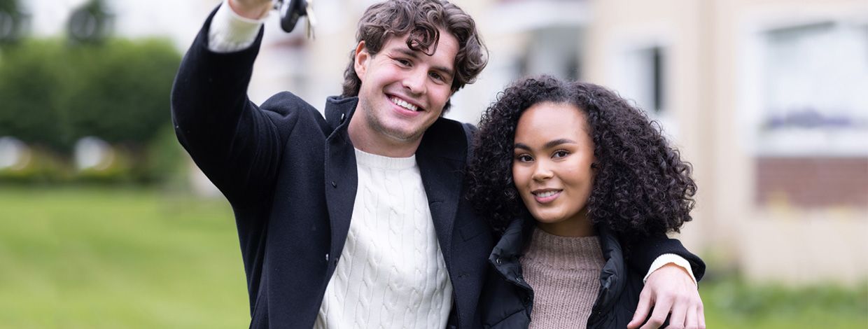 Ungt par foran bygning med husnøkler