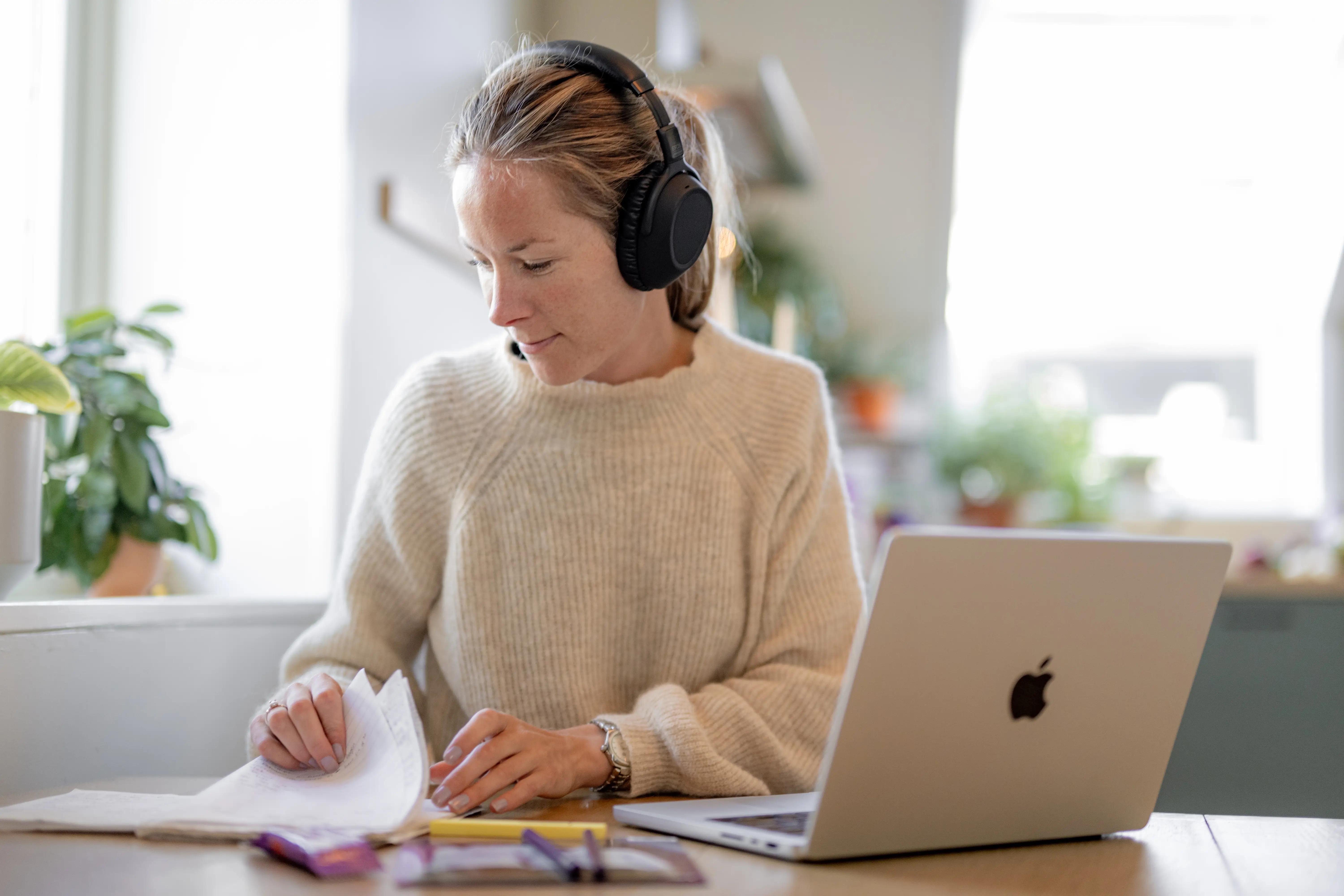 ung dame sitter med headset, pc og papirer