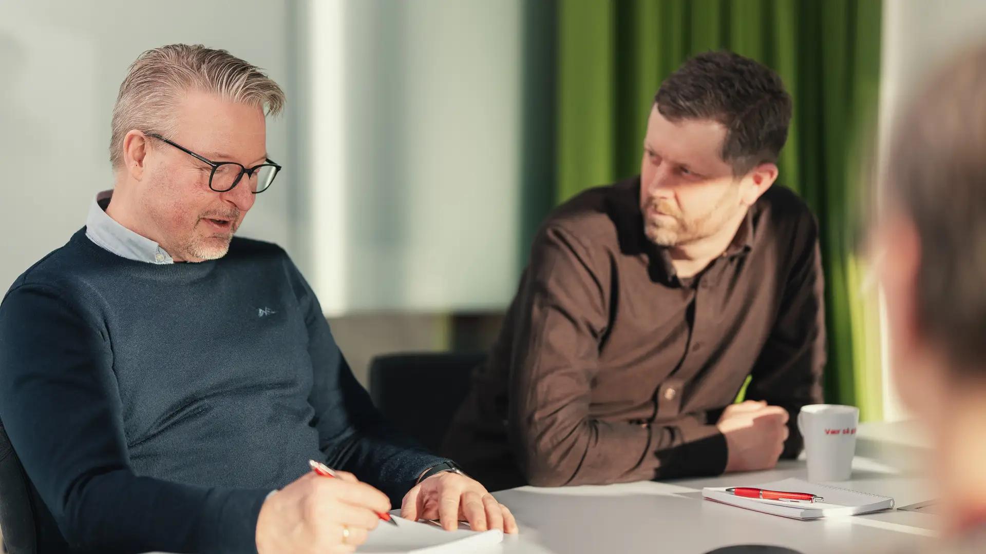 To mannlige styremedlemmer diskuterer i styremøte