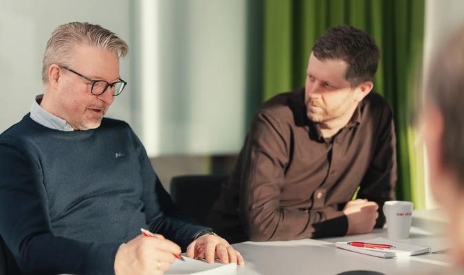 to menn diskuterer i møterom