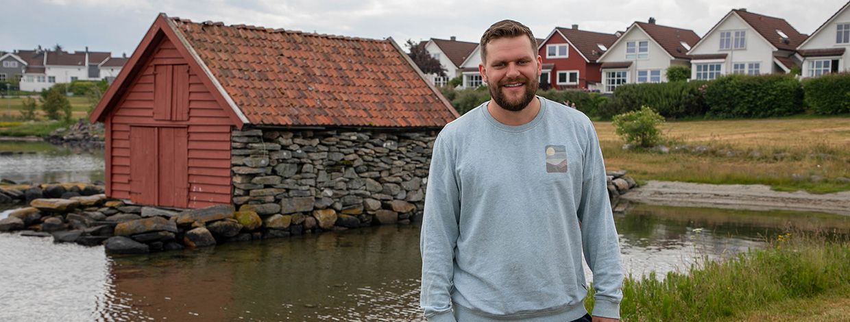 mann foran naust og boligfelt