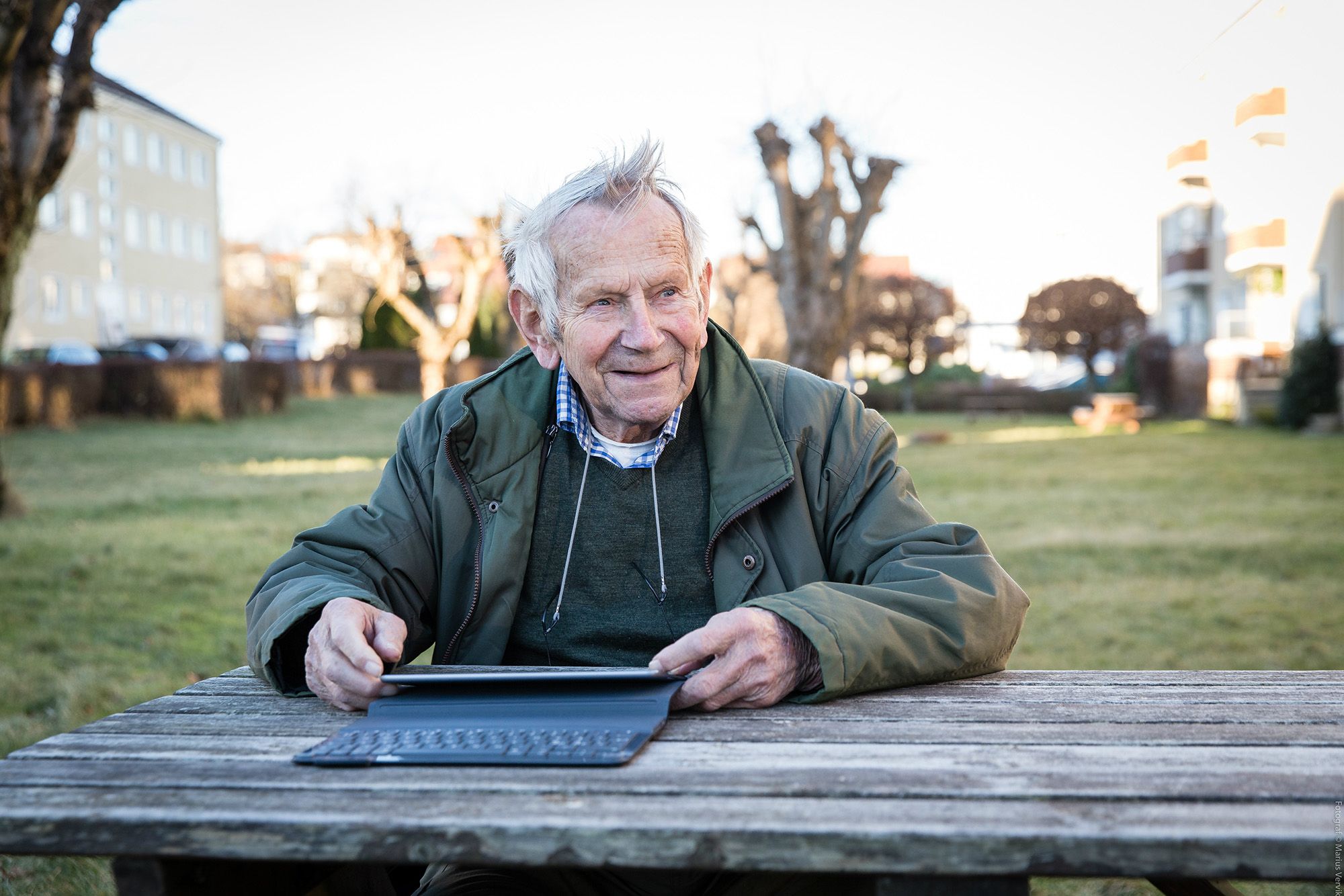 Albert Barstad sitter på en benk med iPad-en sin