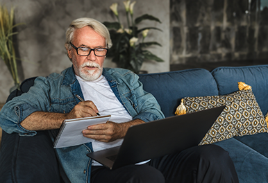 Mann sitter i sofa med pc