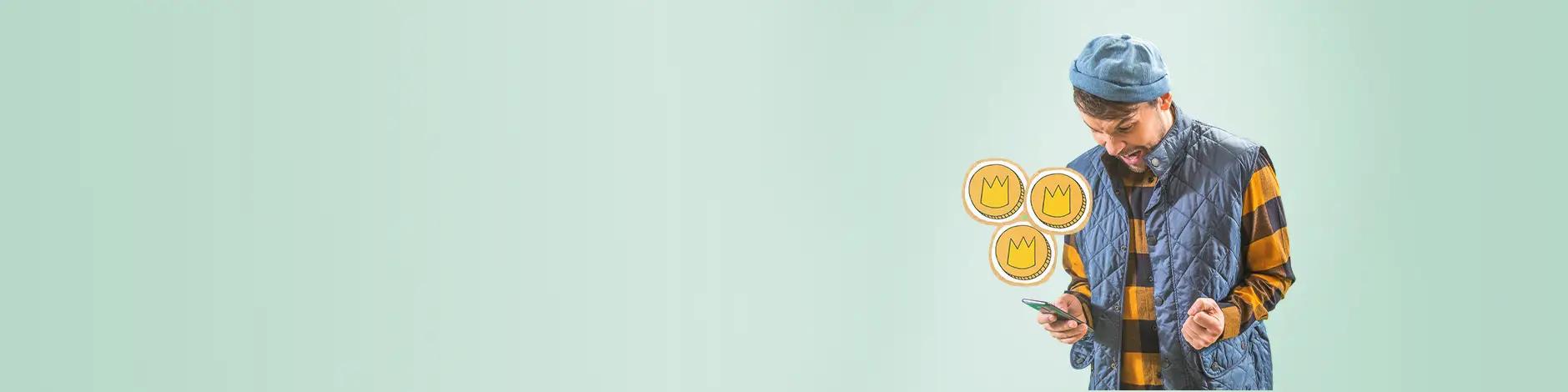 mann jubler og ser på mobil + pappkronestykker