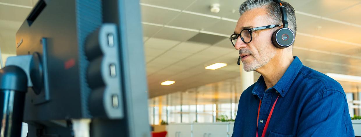 Bate-ansatt med hodetelefoner arbeider på en pc