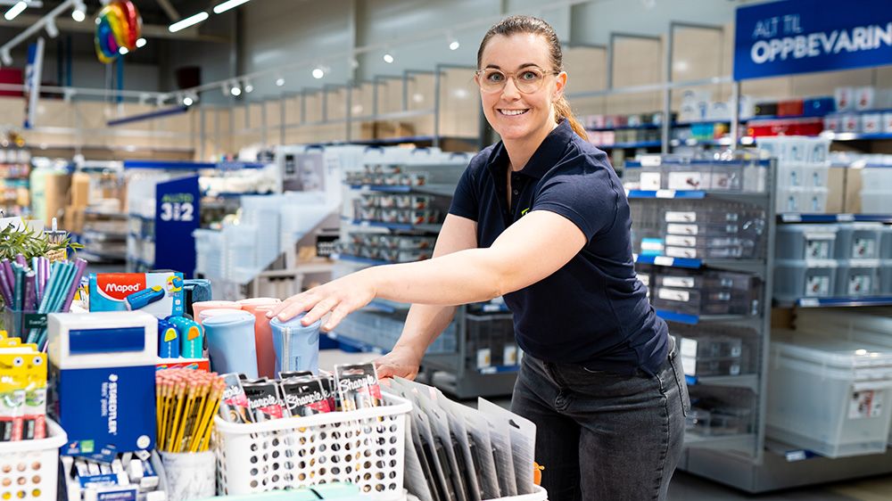 dame smiler og rydder i butikk
