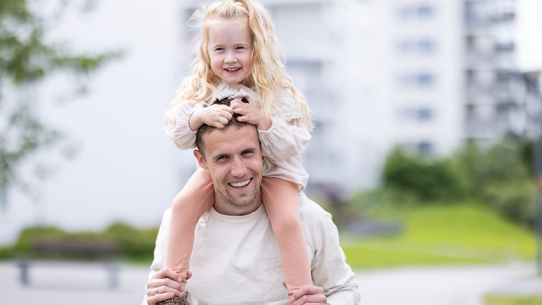 mann med liten jente på skuldrene ute i hage