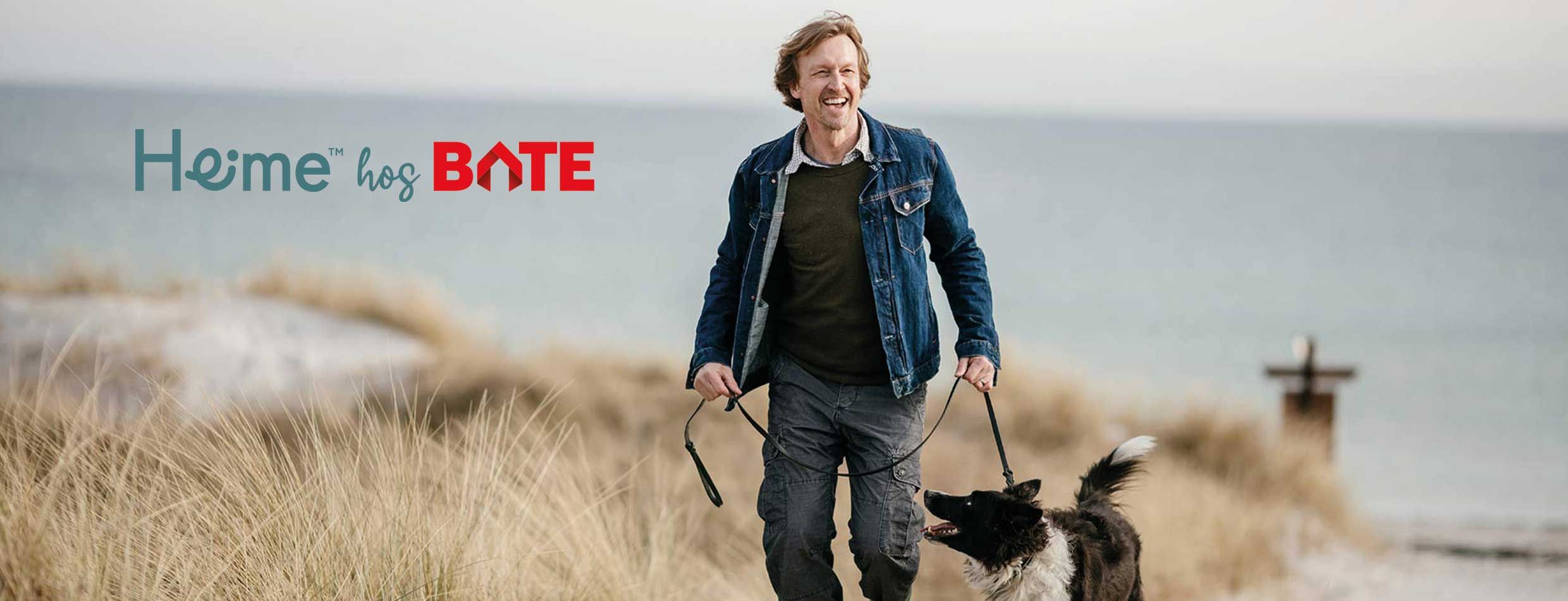 Mann på tur på stranden med hund i bånd