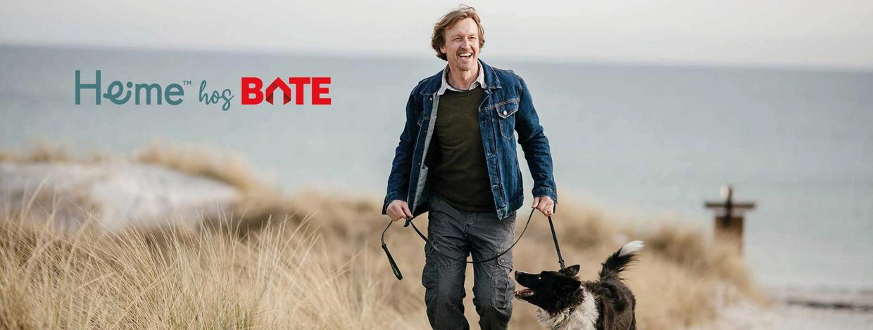 Mann på tur på stranden med hund i bånd