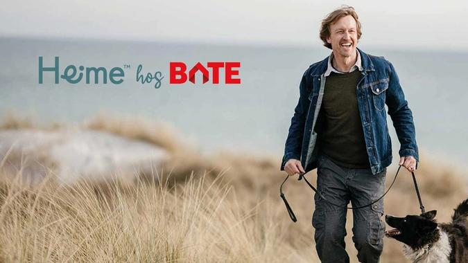 Mann på tur på stranden med hund i bånd