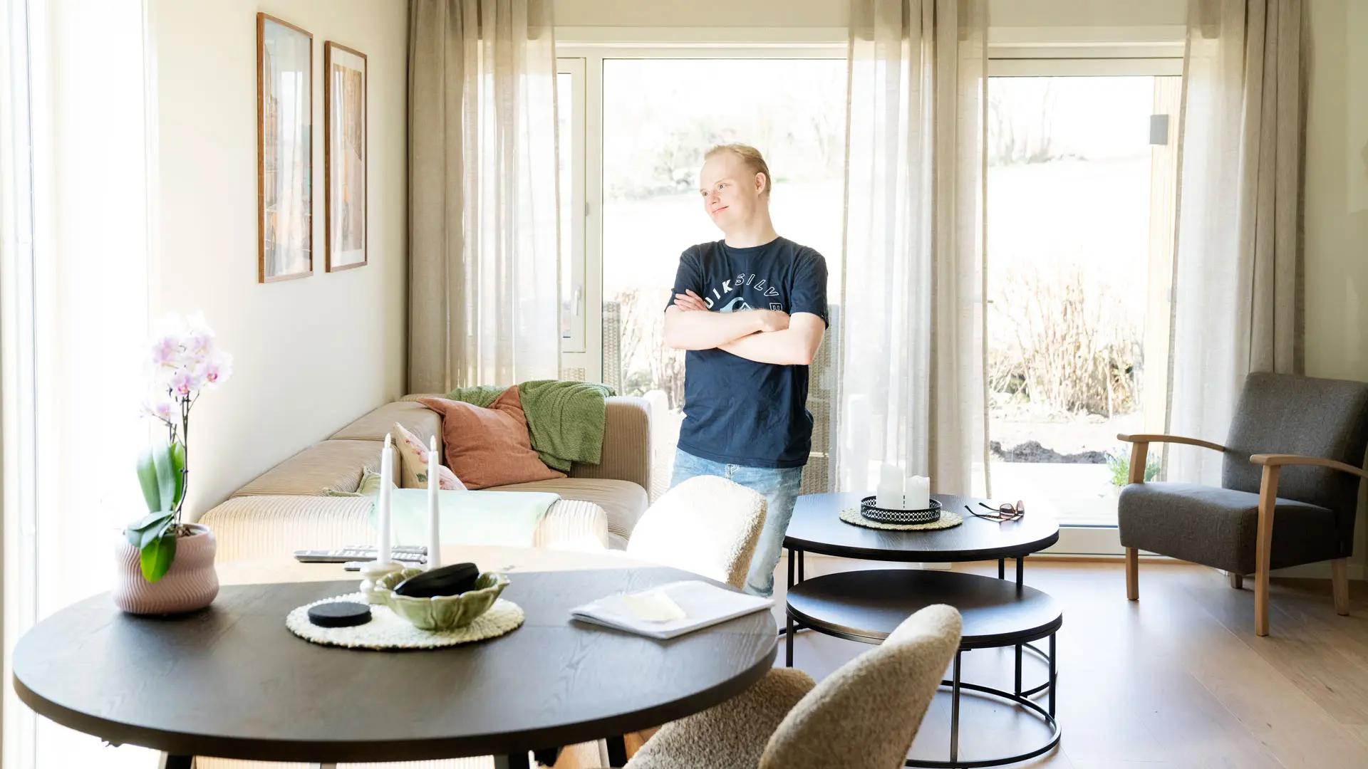 mann står i stue og smiler