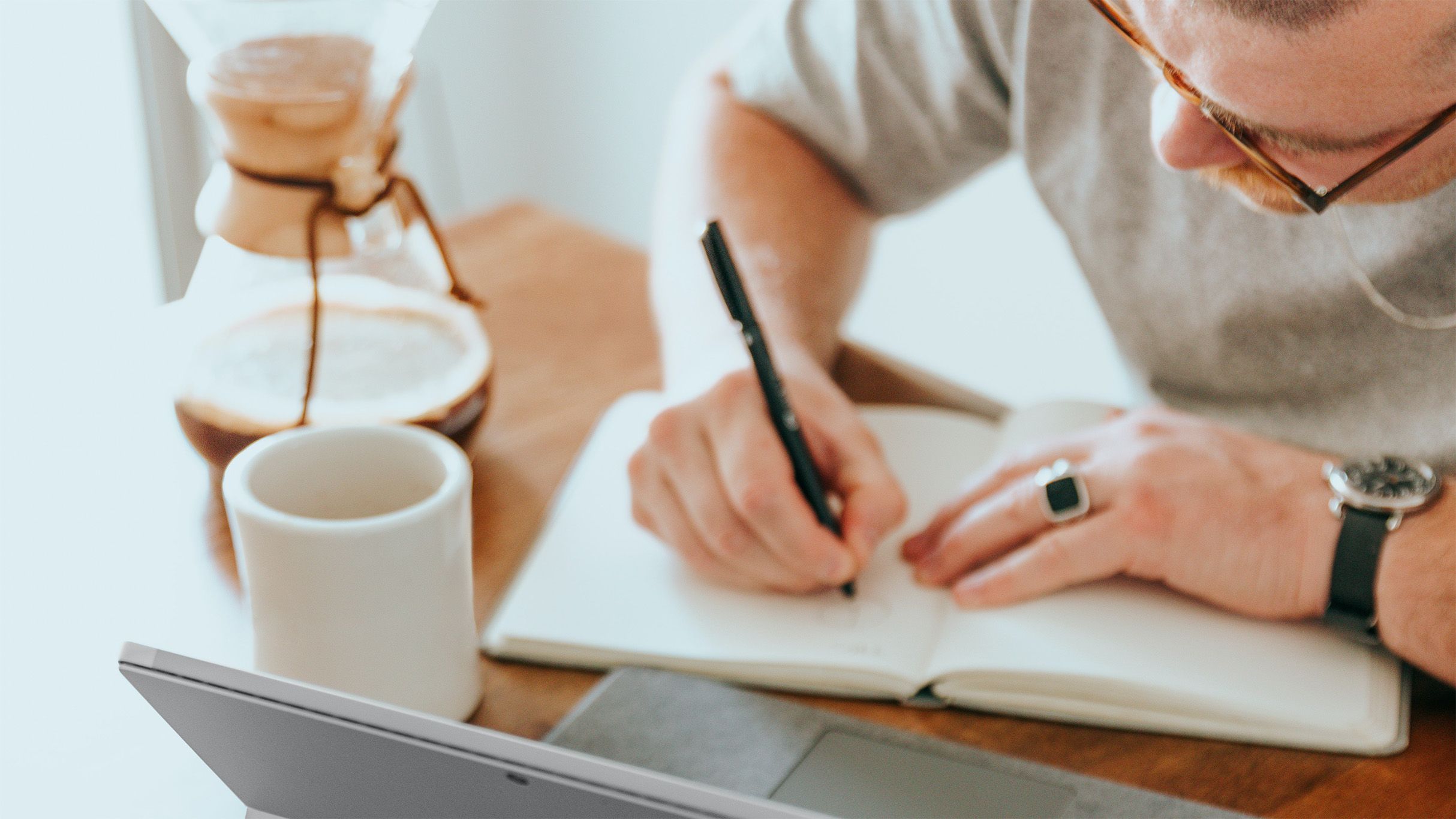 Mann med briller som skriver i en notatbok