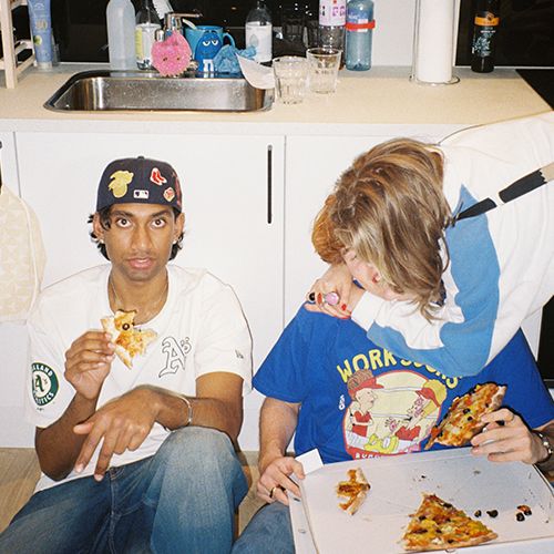 unge mennesker sitter på gulvet og spiser pizza