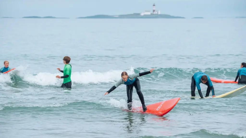 surfere i sjøen med fyr i bakgrunnen
