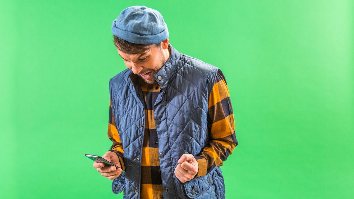 mann ser på mobil og jubler