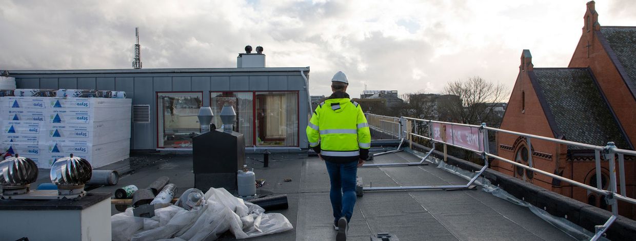 Mann går på befaring på tak