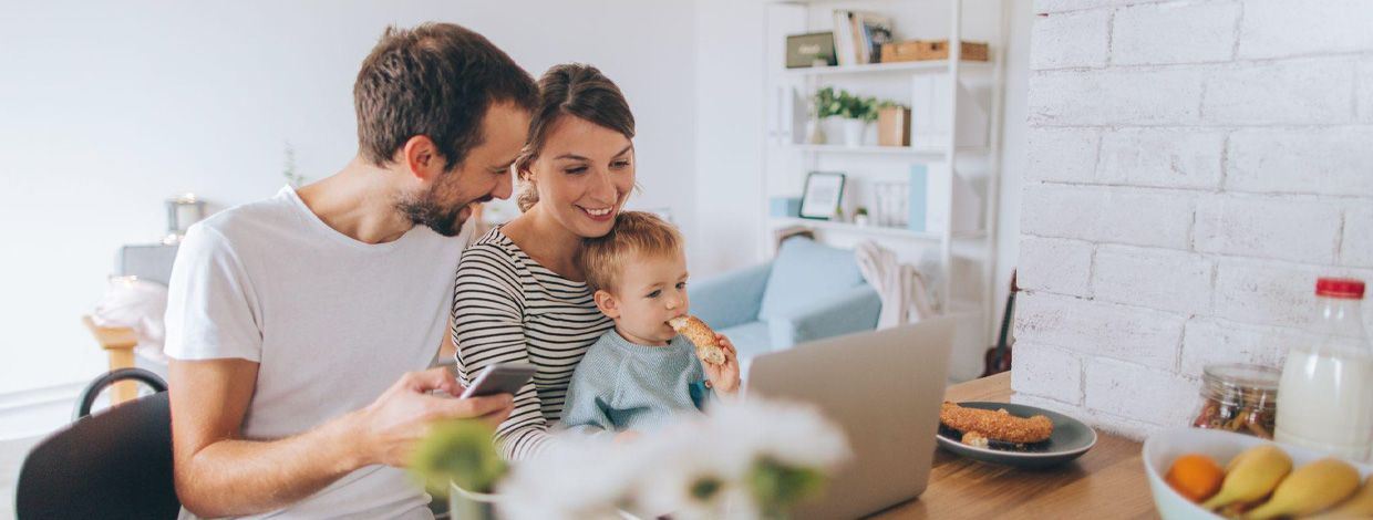 mann, dame og barn foran pc ved frokostbordet