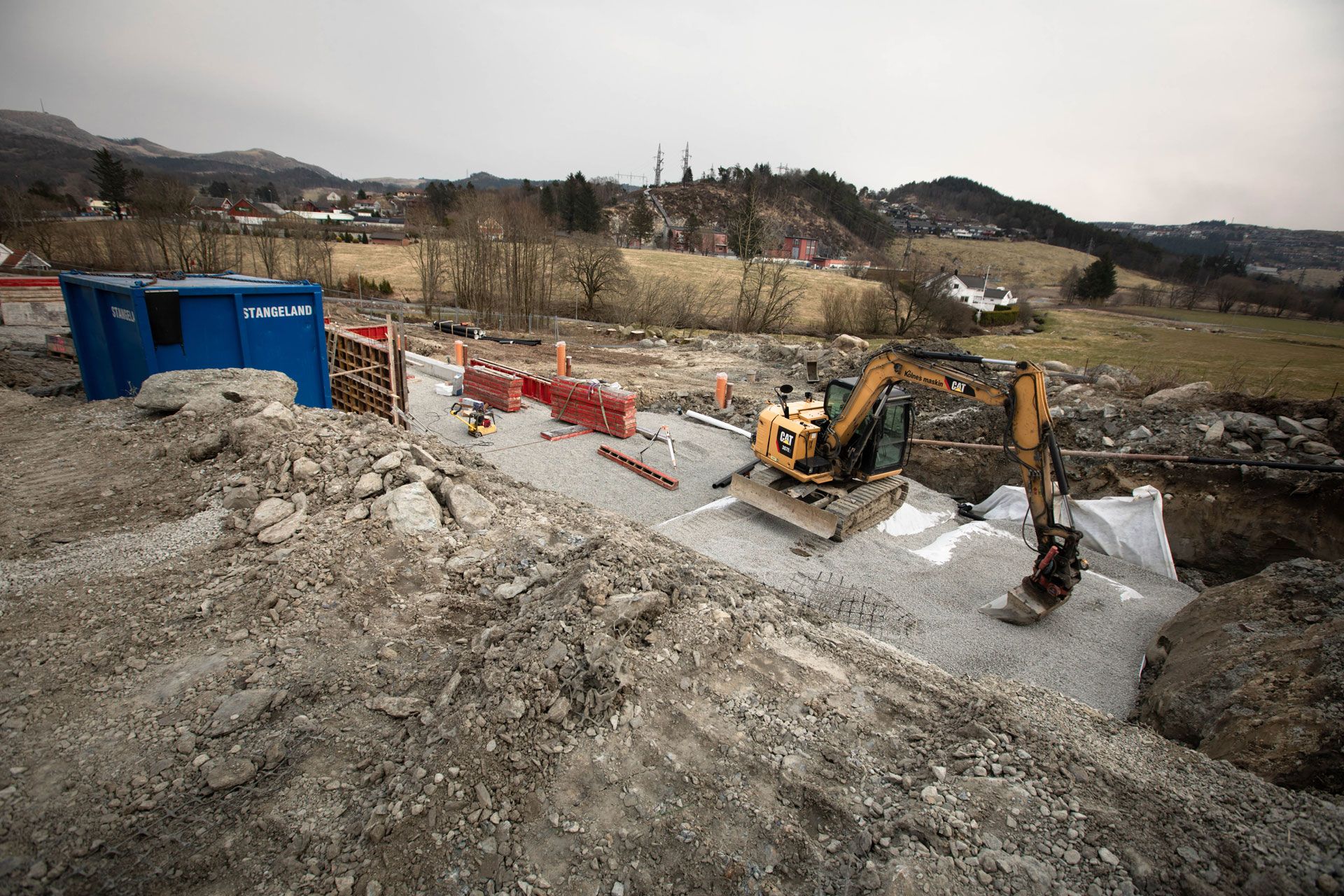 Gravemaskin tar grus over grunnmur på Hovemarka