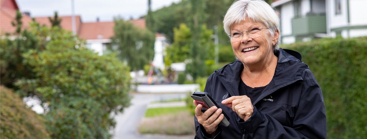 dame som smiler og holder en mobiltelefon