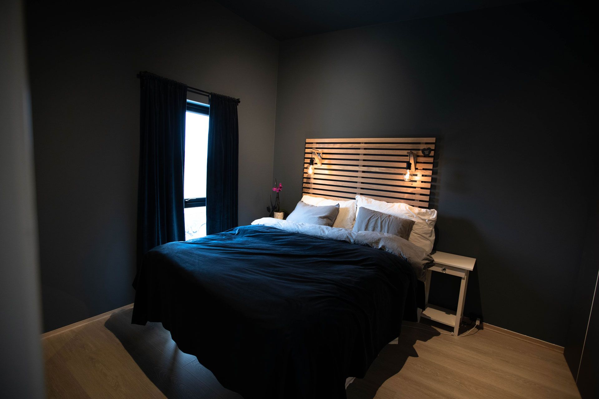Soverom med mørke vegger og hotellseng