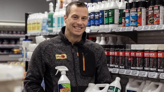 mann i byggevarebutikk smiler med produkter i hendene