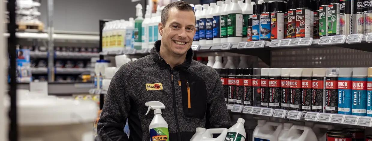 mann i byggevarebutikk smiler med produkter i hendene