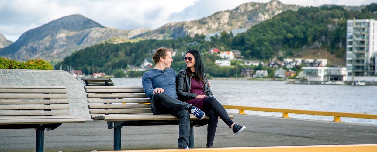 Par sitter på benk ved kaikant