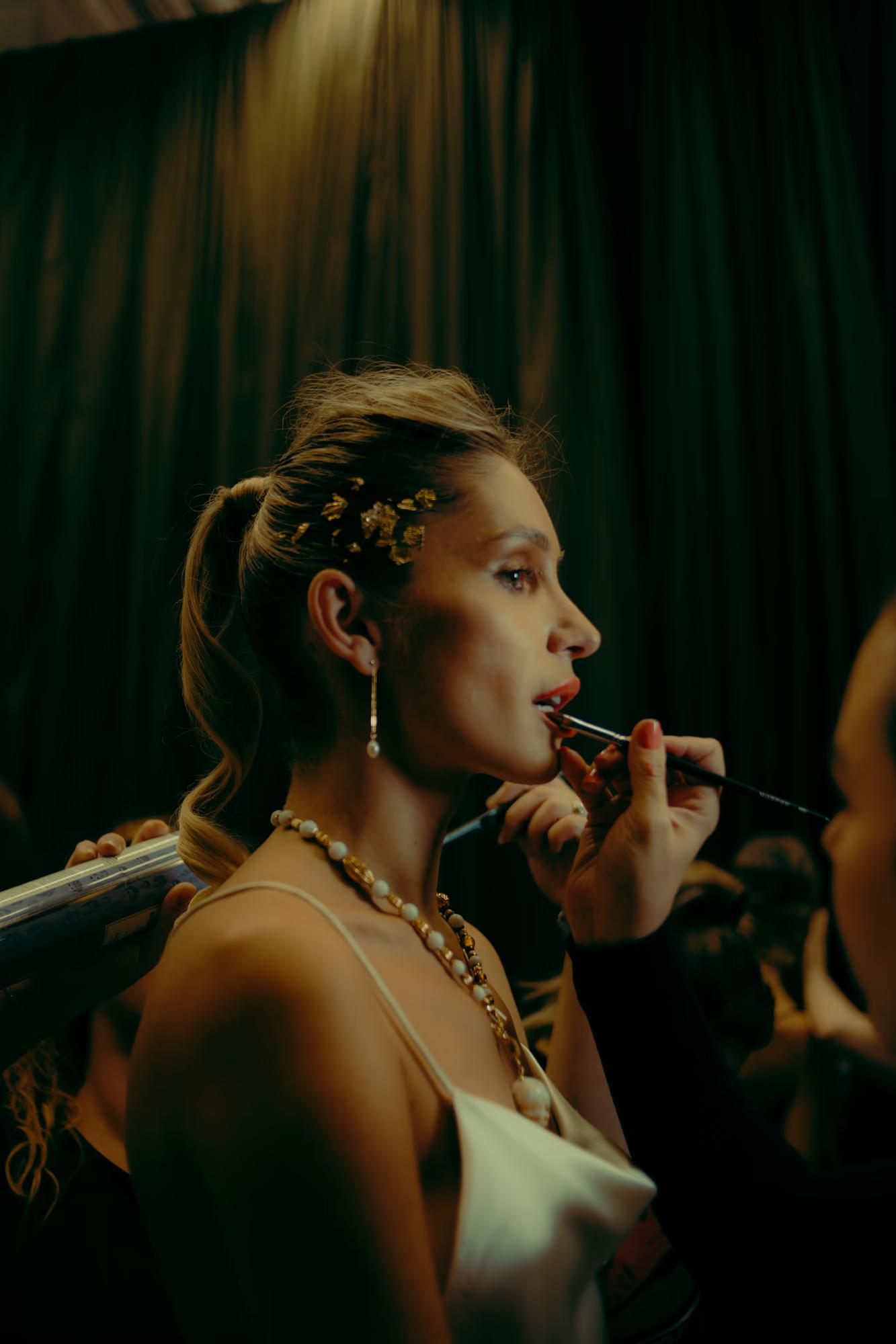 Candid backstage moment: A model receiving final makeup and hair touch-ups before the runway at London Fashion Week.