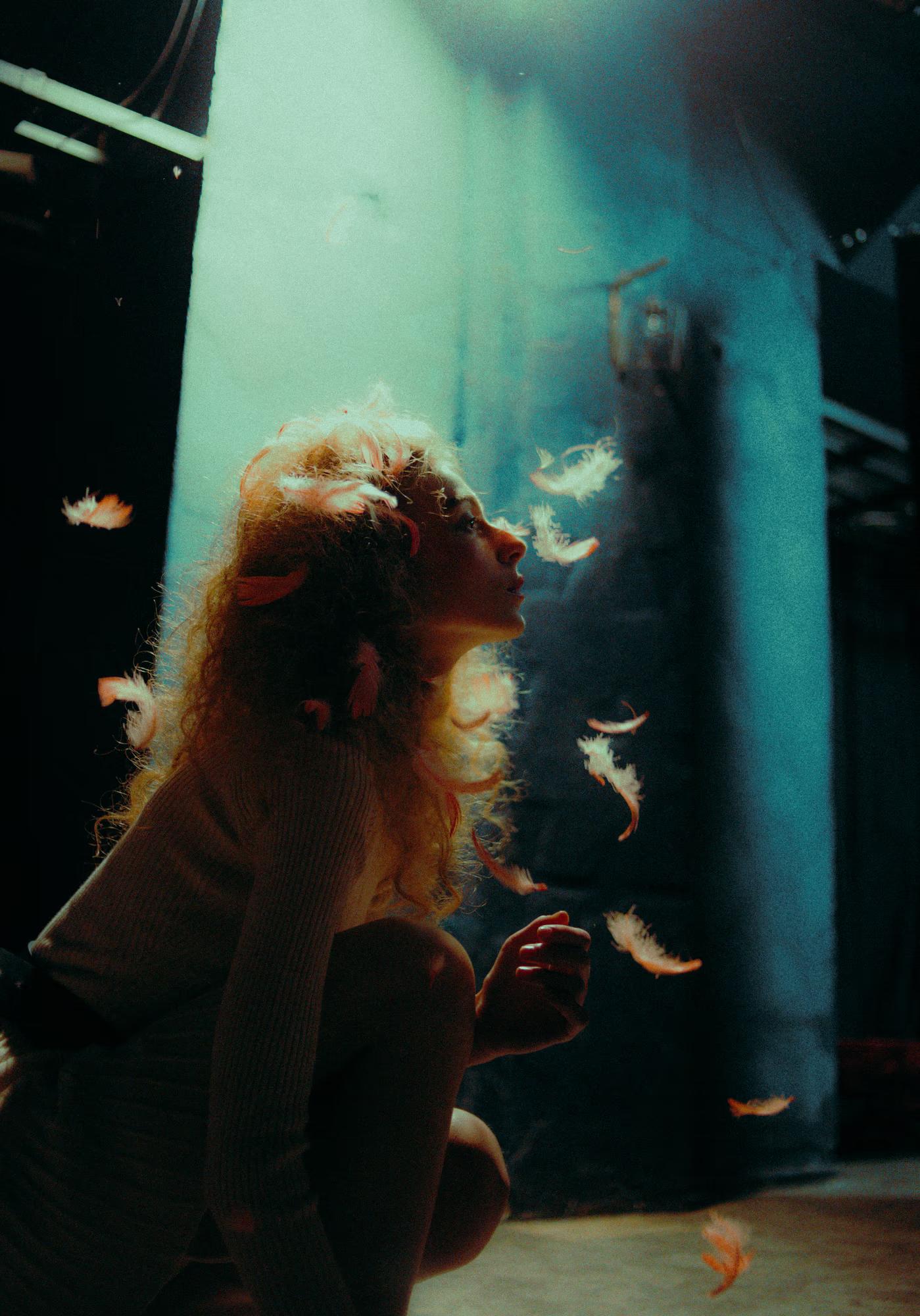 Atmospheric fashion photography featuring a model behind a veil of theater props and light.