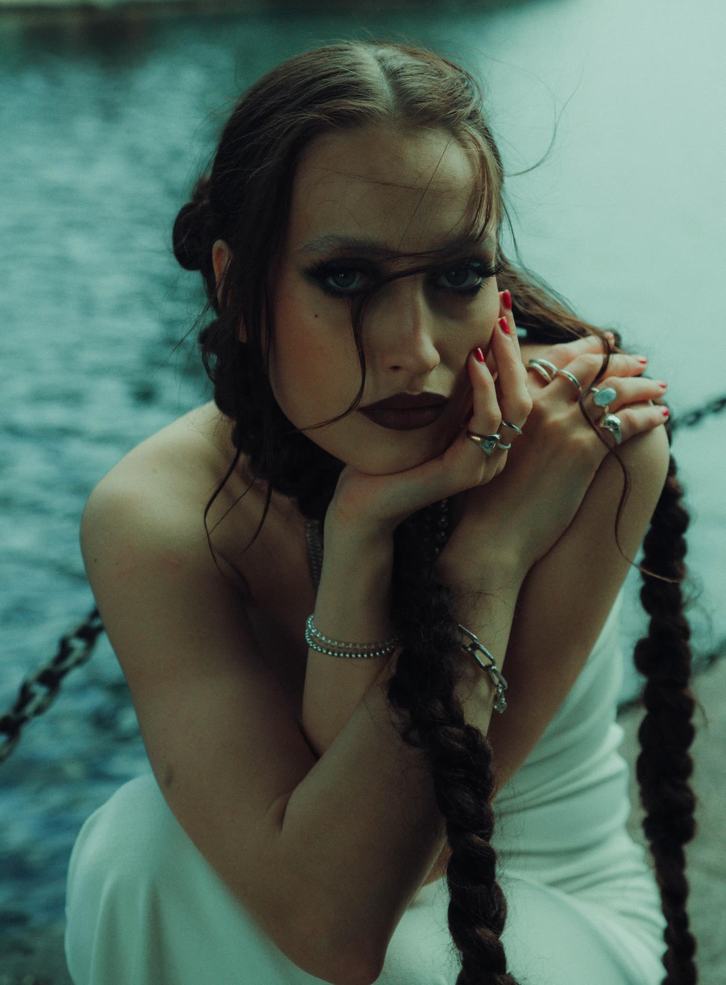 Close-up portrait of woman with hand near face, teal cinematic tones, soft light, Canary Wharf London editorial