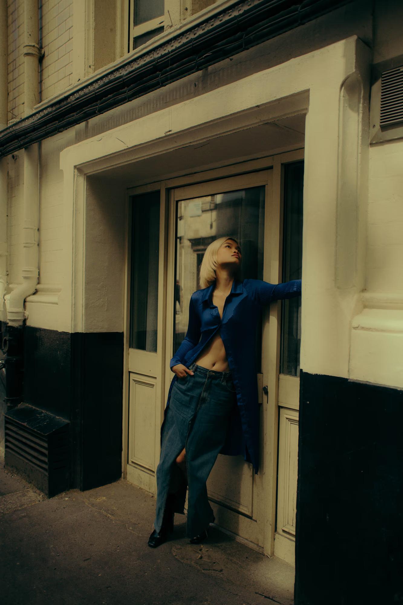 Model standing in doorway, minimalist fashion composition with architectural framing in London streets