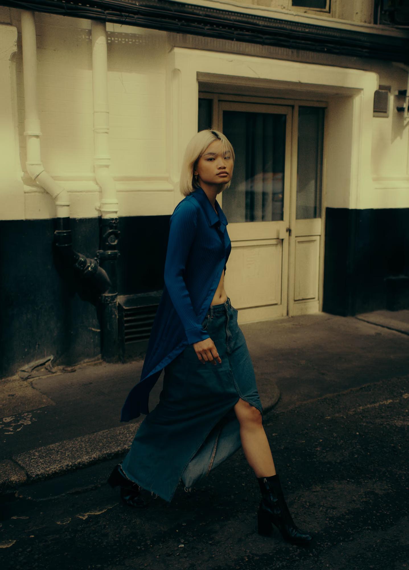 Blonde Philipino woman walking in blue outfit, cinematic street fashion scene in movement in London