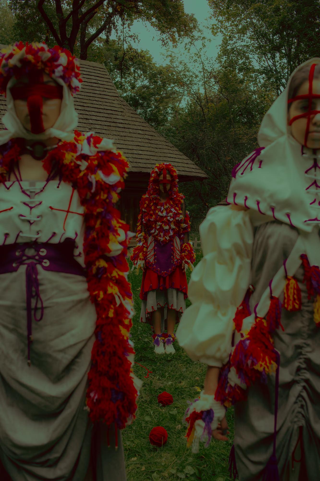 Detail-oriented fashion shot highlighting the textures of white puff sleeves and red floral crowns in a historic open-air museum setting.