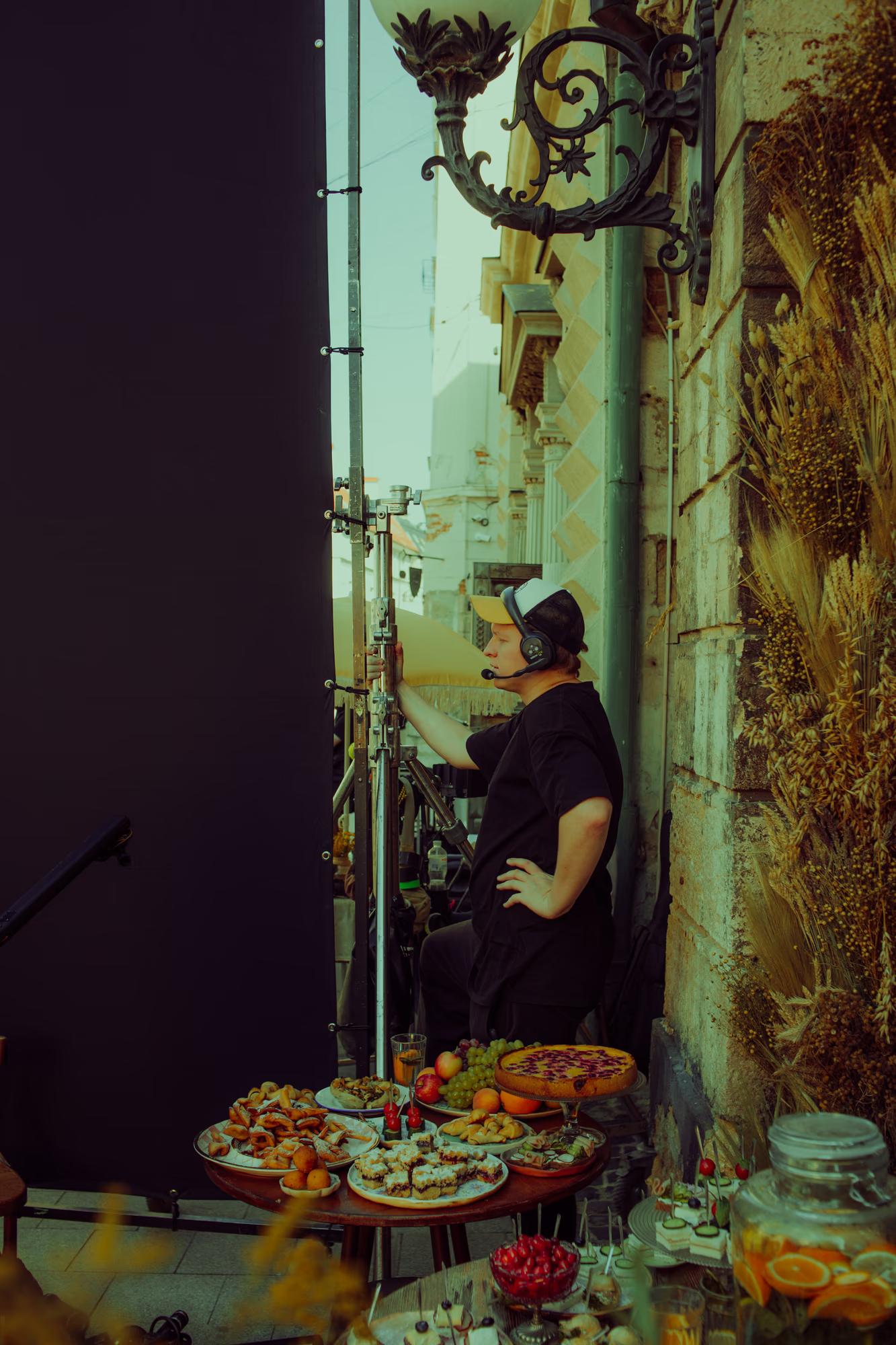 A camera operator capturing a close-up shot of an actress in a dramatic, shadow-filled setting.