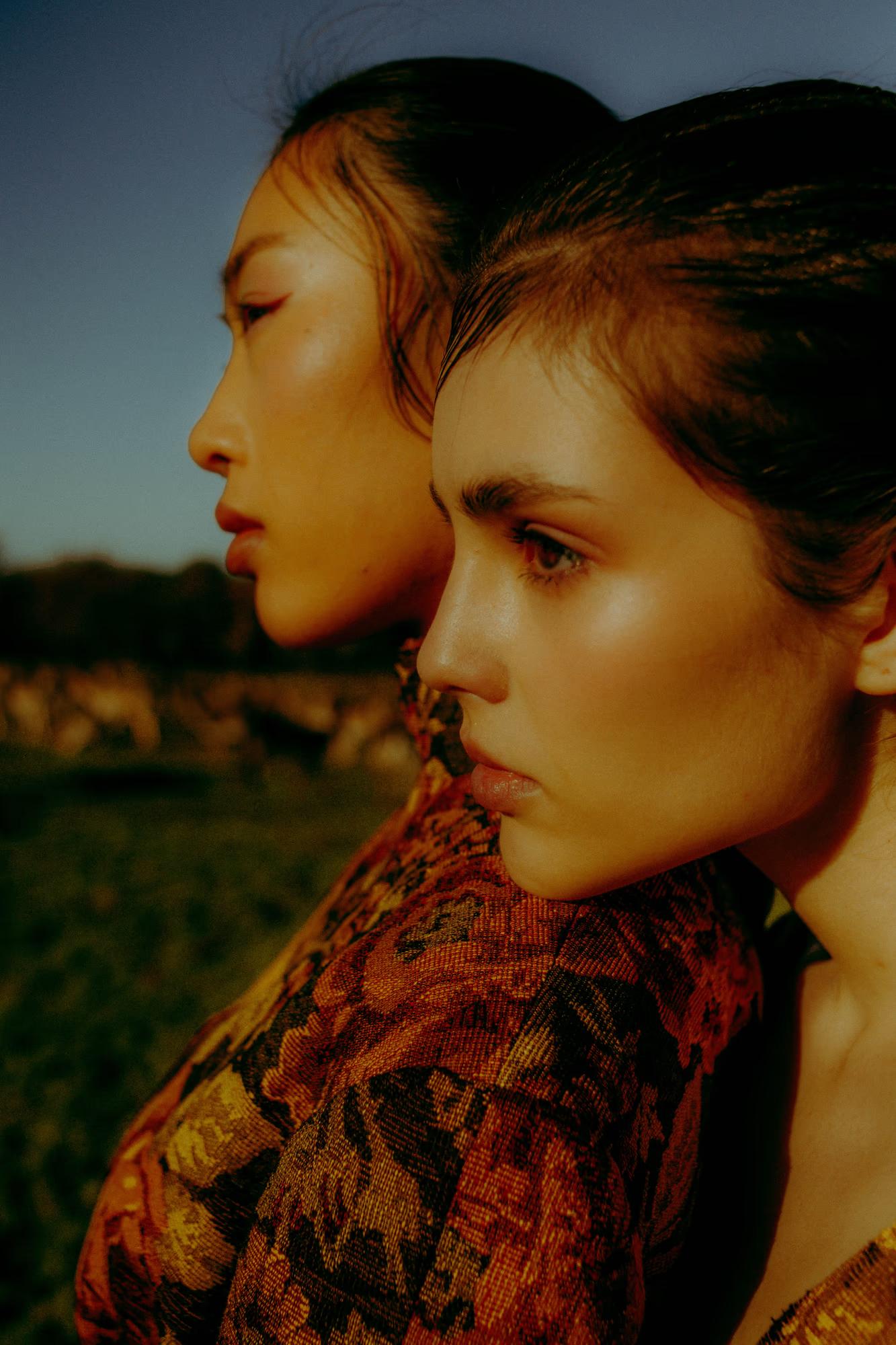 Close-up side profile fashion portrait of woman in rich red and orange floral designer outfit, dark moody background, Richmond Park London campaign