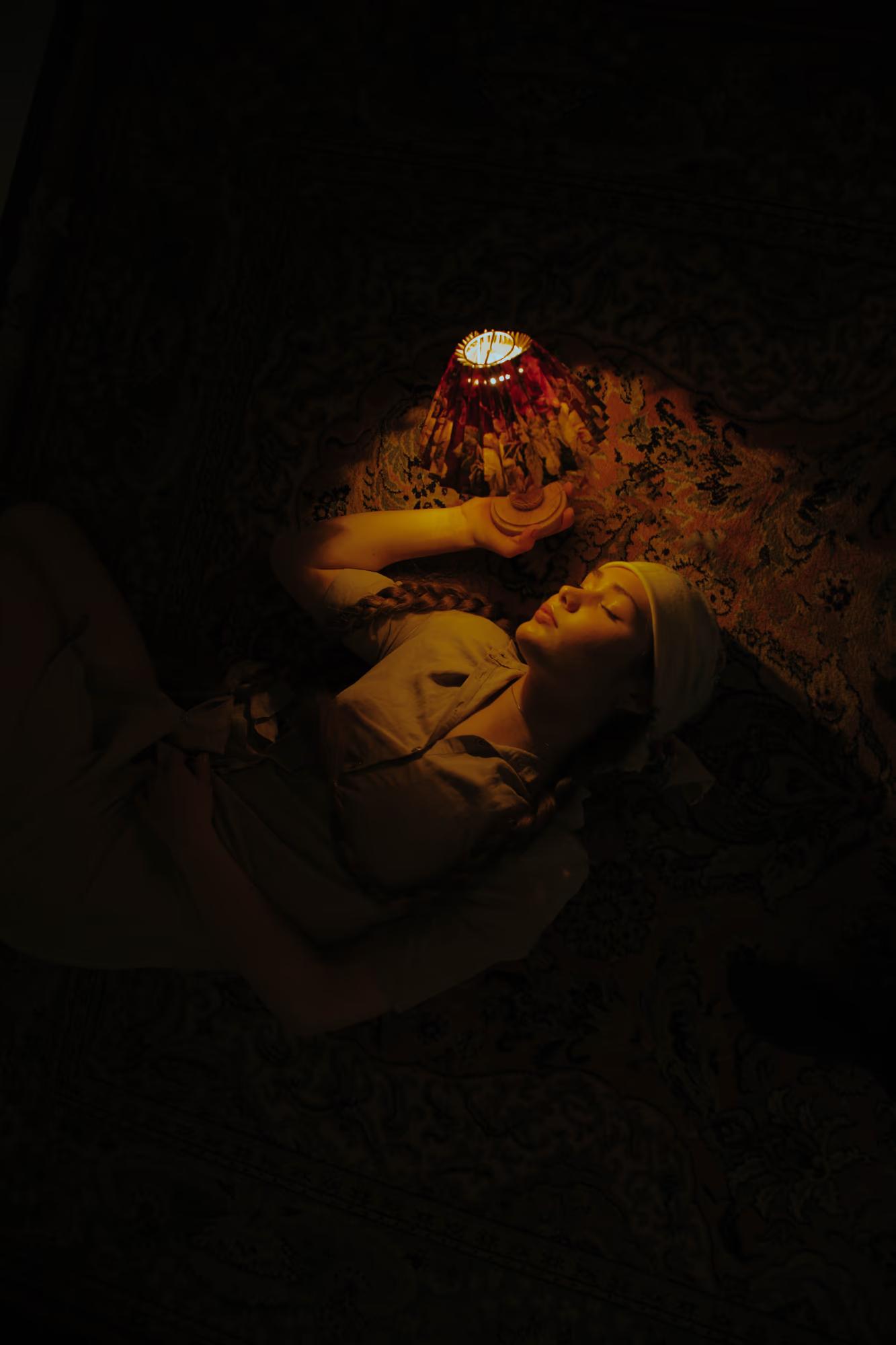 Medium fashion art shot of woman in dark interior holding candle, mysterious moody candlelight, dramatic shadows, ethno art editorial