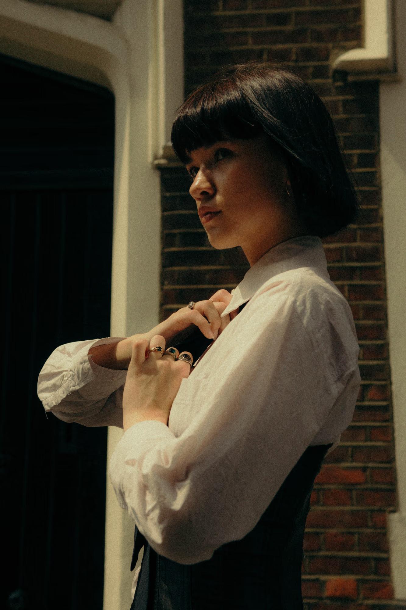 Close-up fashion portrait of woman in white shirt with androgynous styling, soft natural side light, intimate editorial, Shoreditch London
