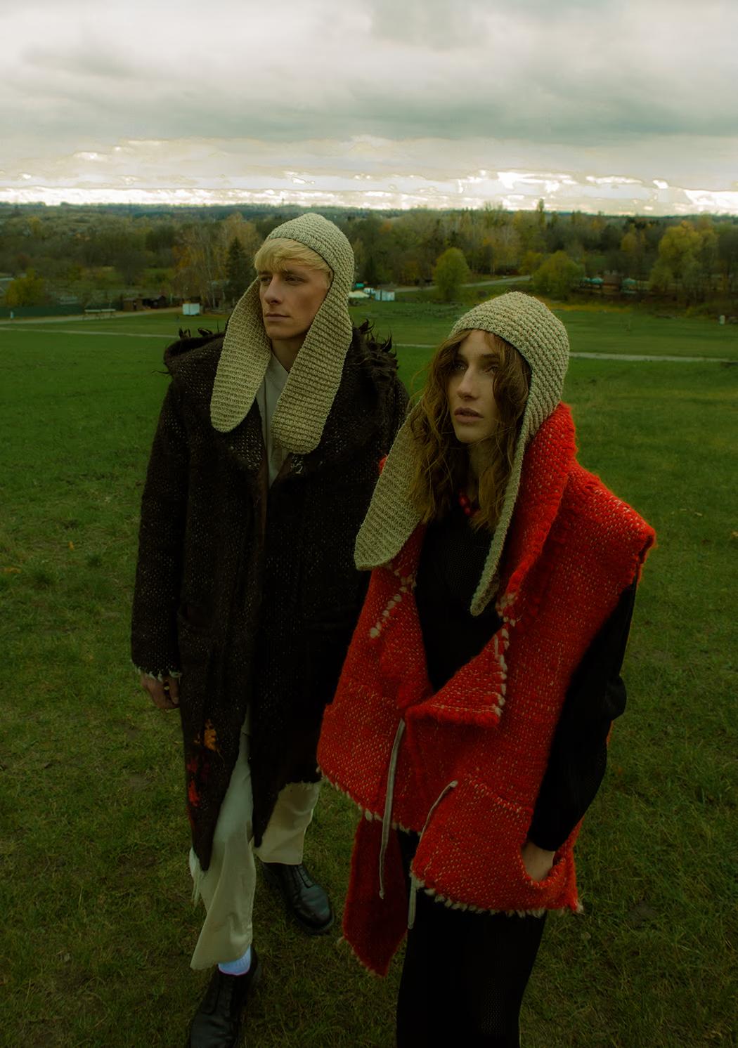 Full-length shot of models in minimalist silhouettes with red accents standing in the vast fields of the Pirogovo estate.