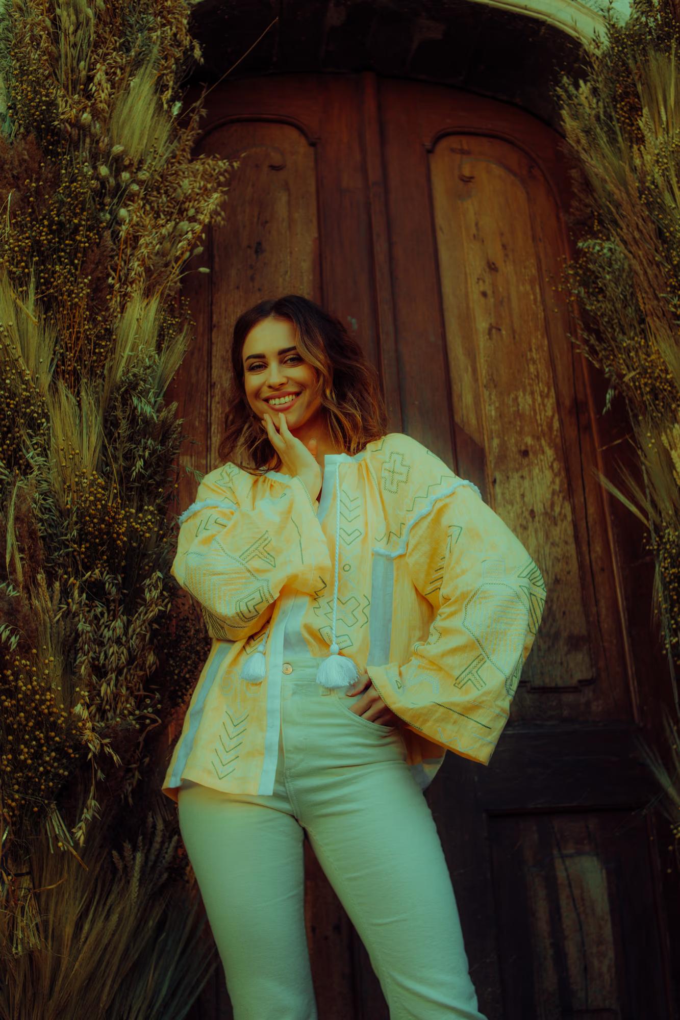 Portrait of an actress in an ivory suit posing in a historic wooden doorway, high-fashion film aesthetic.
