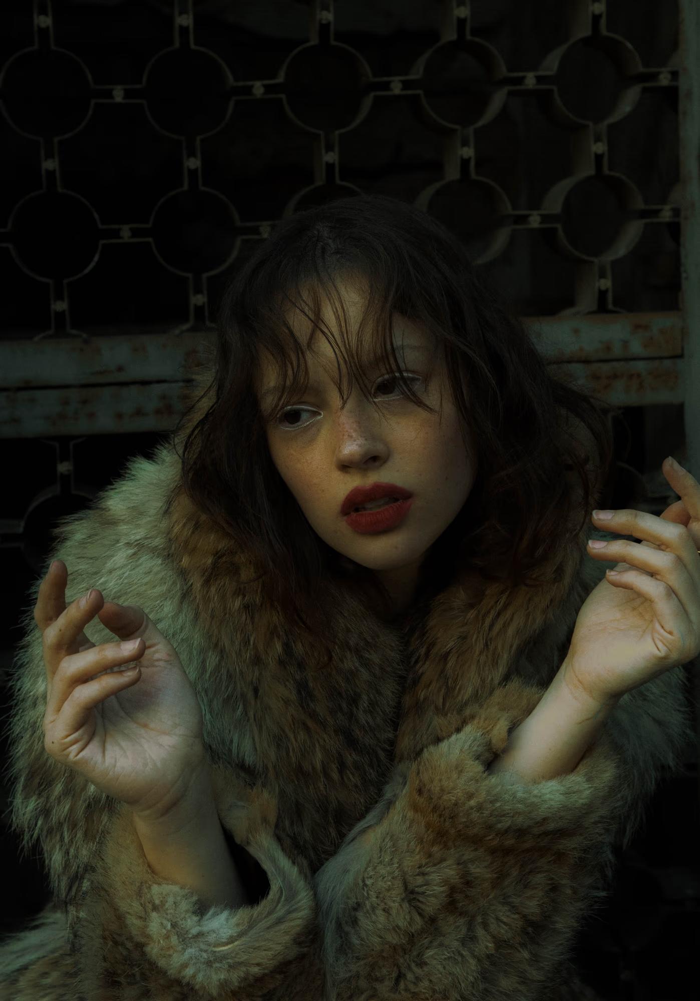 Close-up fashion art portrait of woman in fur coat with intense expression, dark moody forest background, dark fantasy editorial
