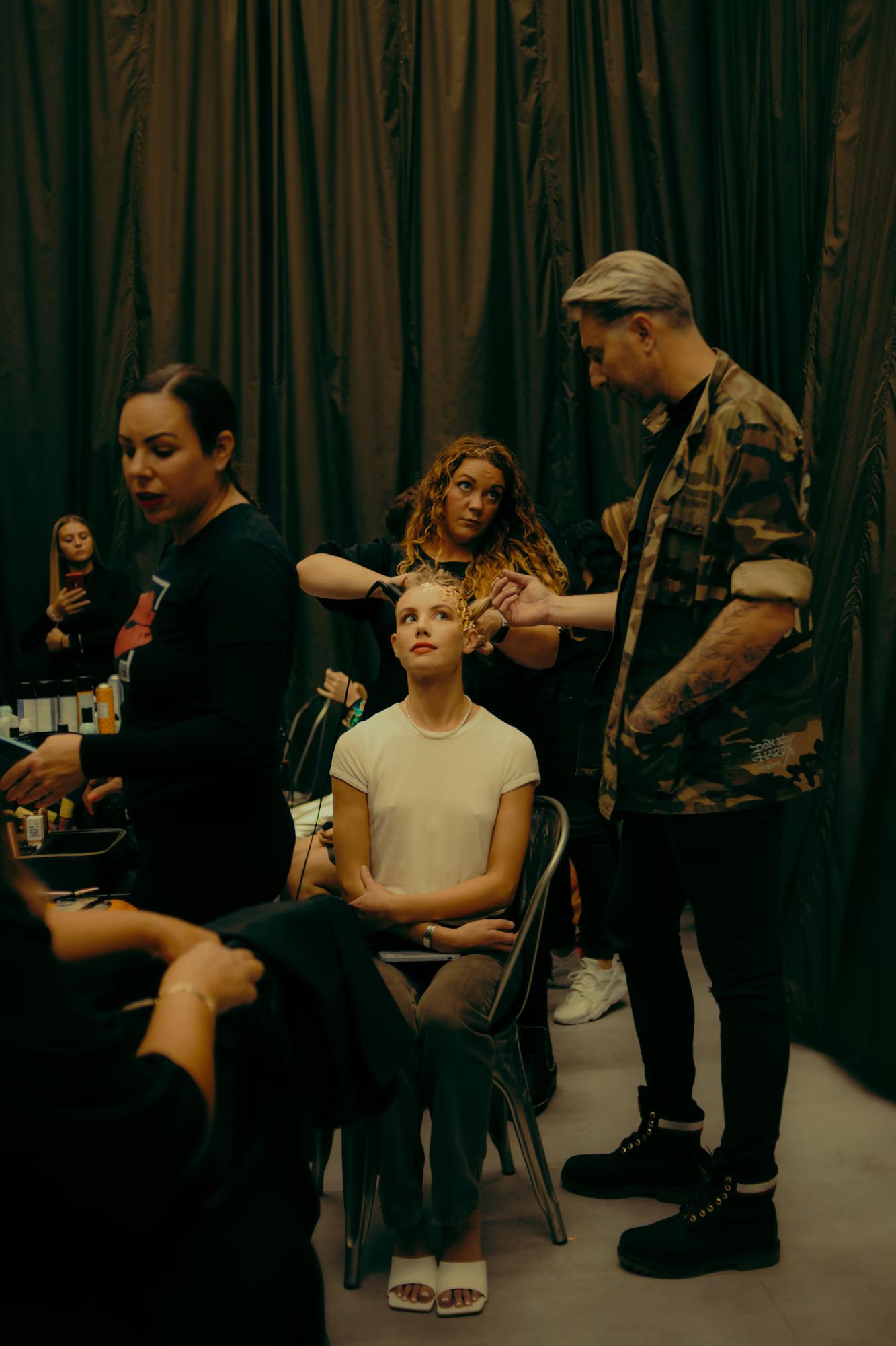 Candid shot of the fashion crew and models gathered in the prep zone, showcasing the chaotic beauty of fashion week.