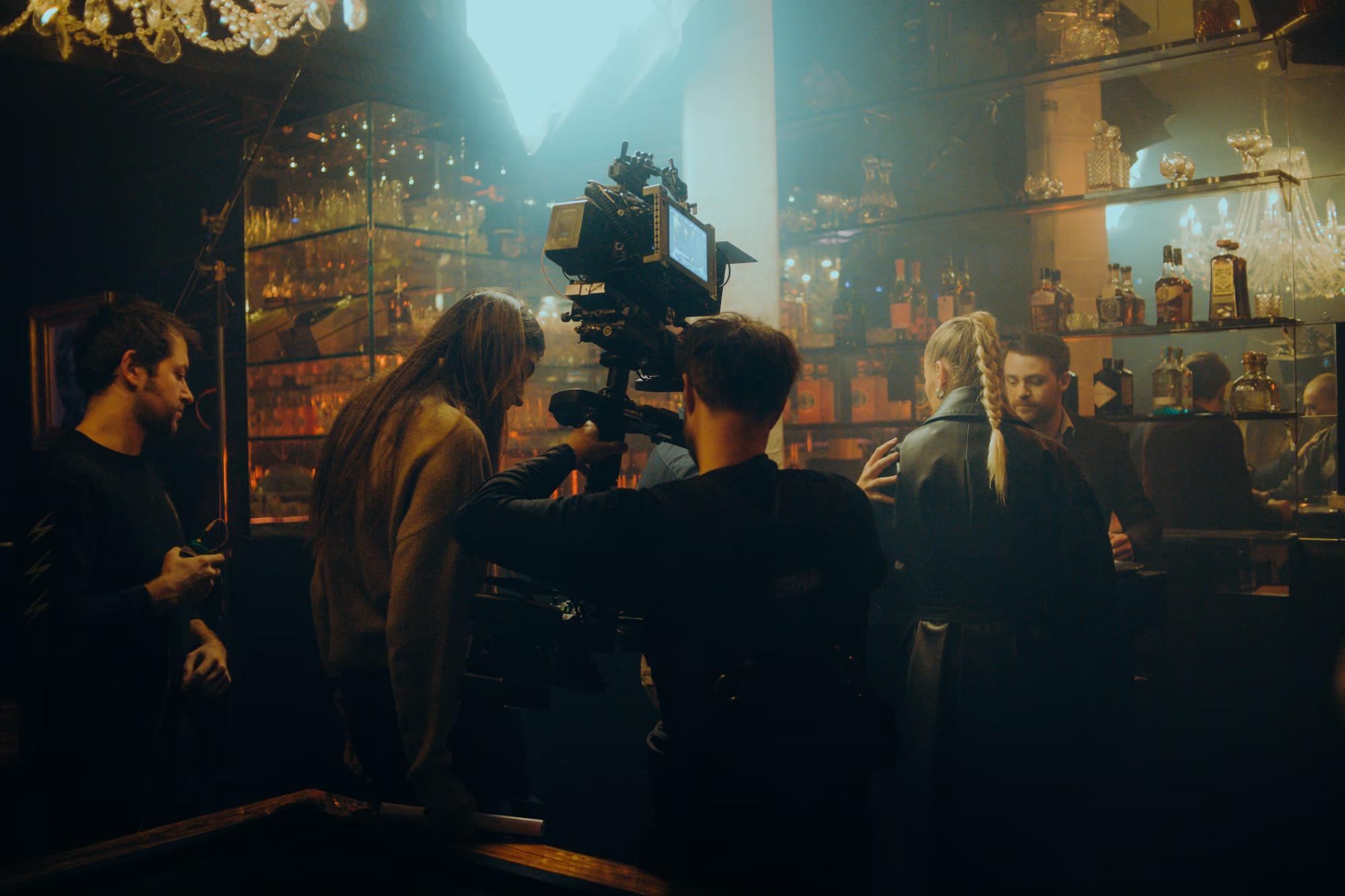 Cinematic wide shot of a film set interior with professional lighting rigs and crew preparing for an action sequence.