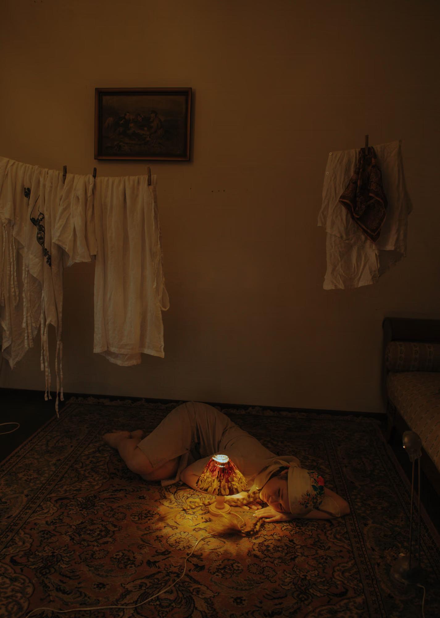 Full body fashion art shot of woman in white traditional outfit with candles arranged on floor, warm golden candlelight, dark dramatic interior, ethno fashion art