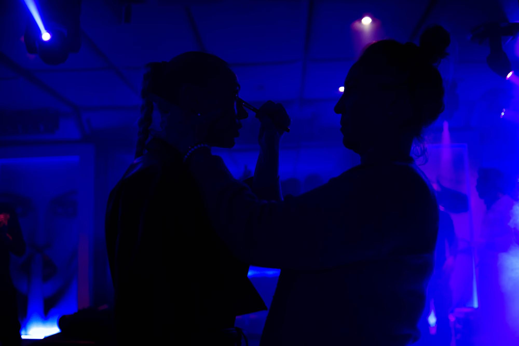 Silhouette of two actors in a mid-fight pose against a vibrant blue-lit background on an action film set.