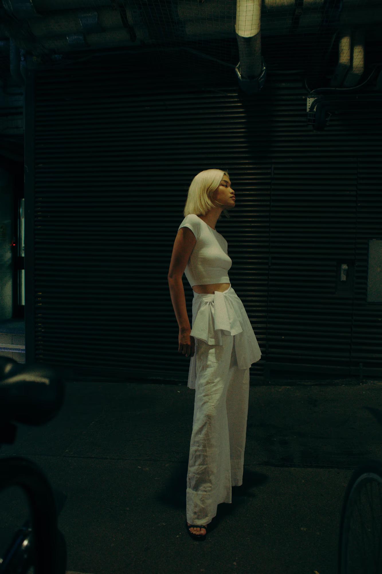 Full body shot of blonde model in white outfit, minimal fashion editorial, cinematic lighting